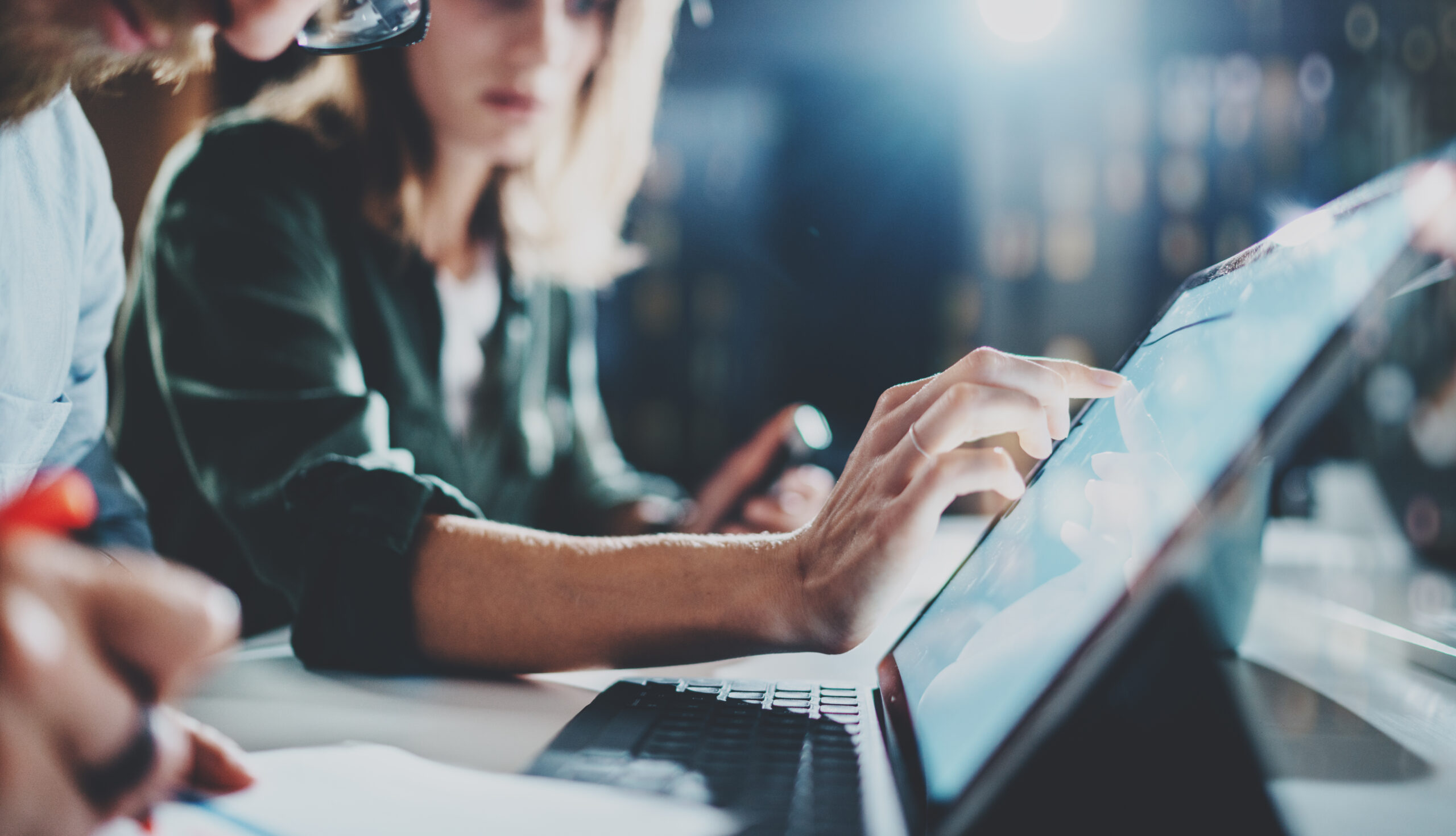 Woman pointing on digital tablet screen at night office .Horizontal.Blurred background.Flares.